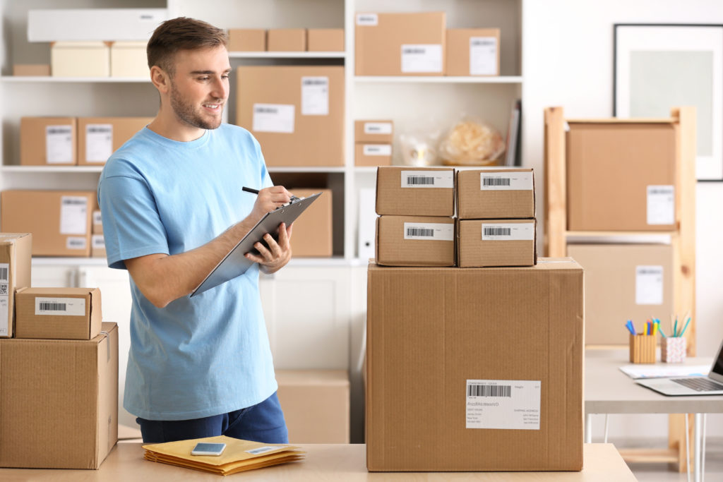 Young man preparing parcels for shipment to client in home office